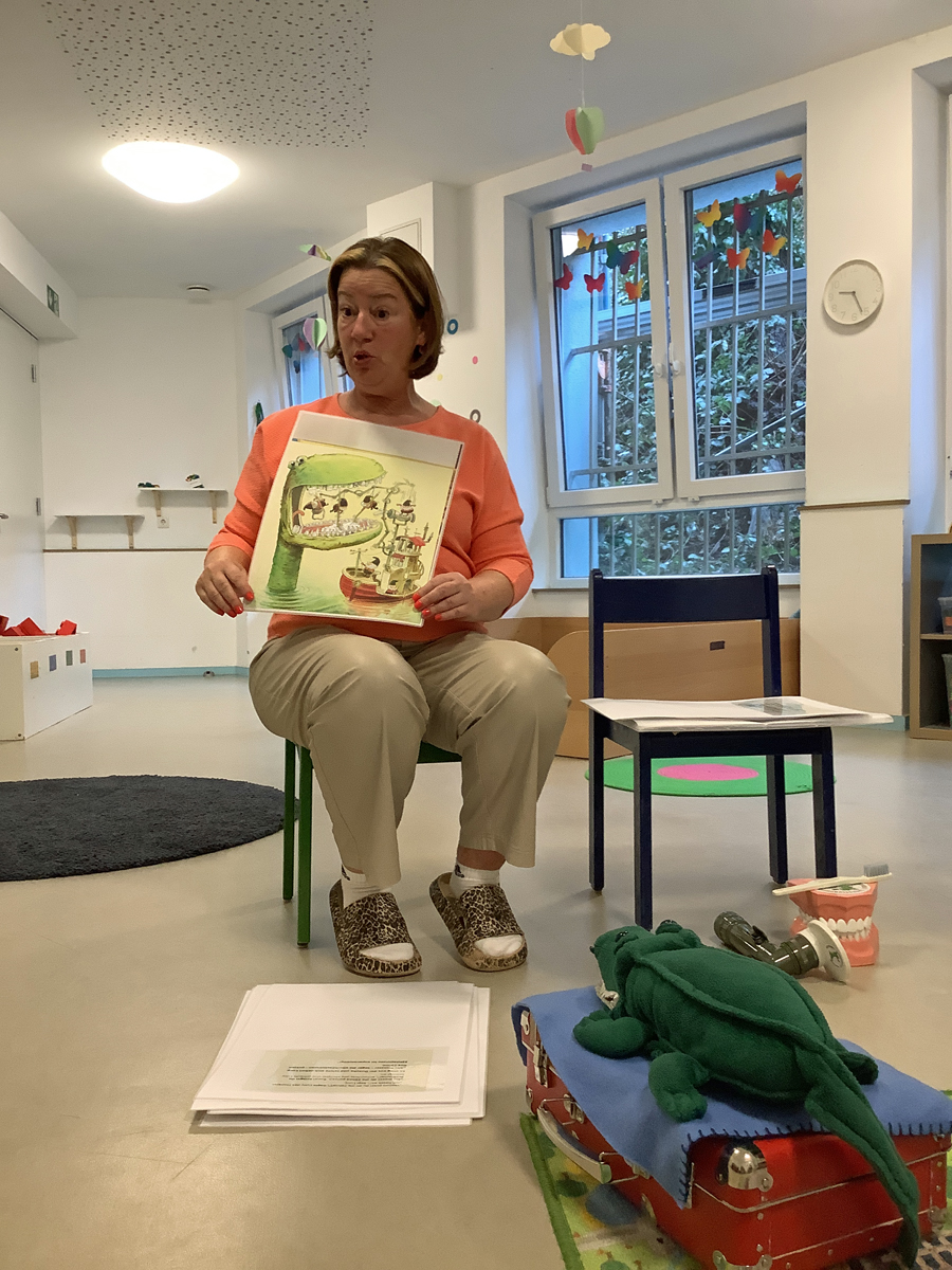 Die Mitarbeiterin des Mundhygienezentrums zeigt Kindern ein Bilderbuch zum Thema Zahngesundheit