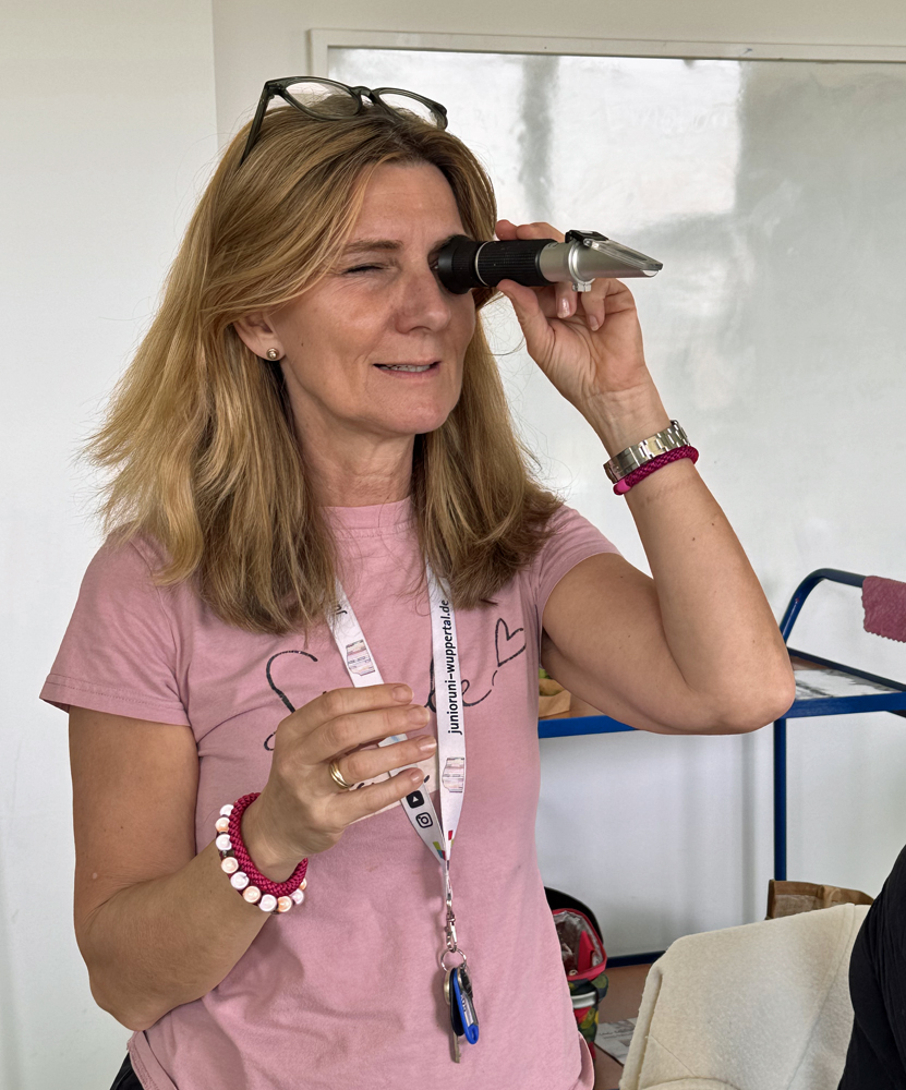 Die Dozentin haelt sich ein Zuckermessgeraet vors Auge