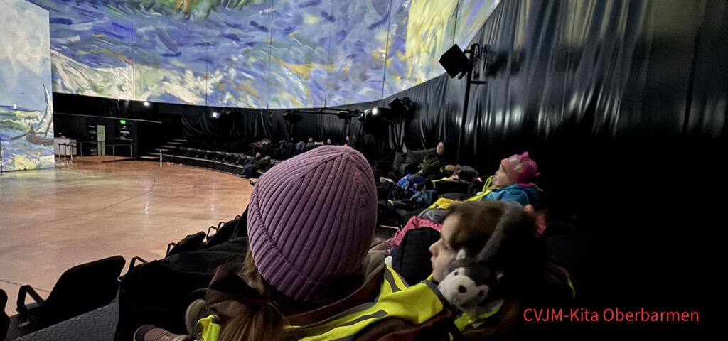 Kinder sitzen auf Sesseln im Visiodrom Wuppertal und schauen die Van-Gogh-Show an
