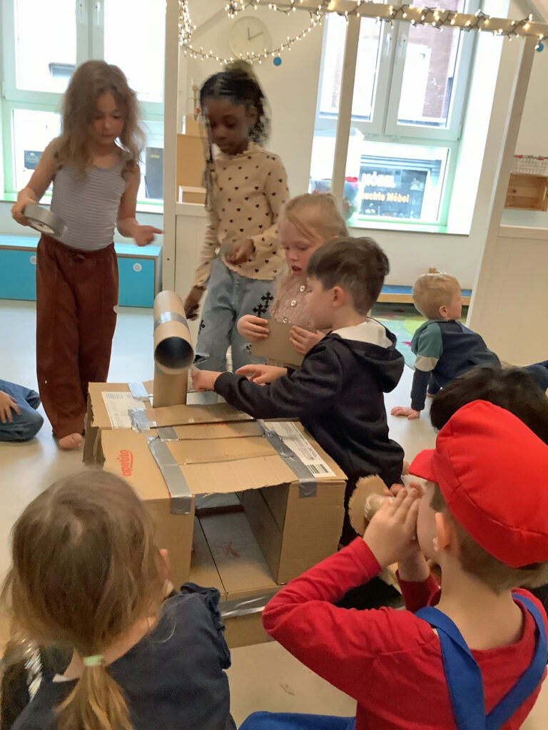 Kinder basteln aus Pappkartons, Papprollen und Klebeband eine Wunschmaschine