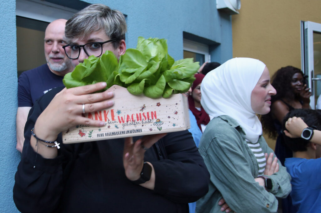 Eine Erzieherin hat als Abschiedsgeschenk eine Holzkiste mit Salatkoepfen erhalten