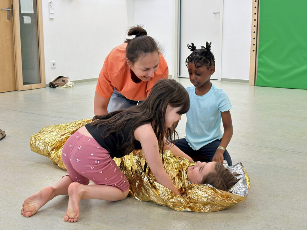 Kinder haben im Erste-Hilfe-Kurs ein Kind in eine Rettungsdecke eingewickelt
