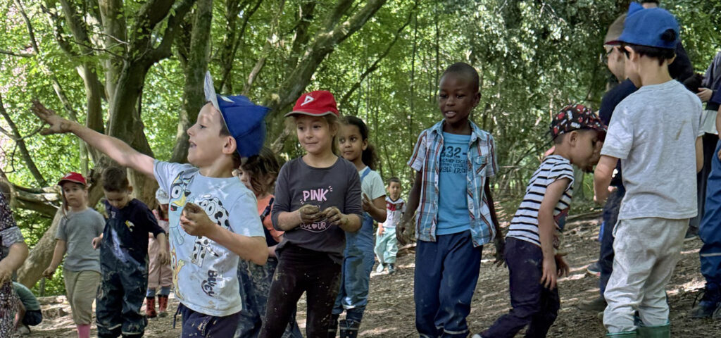 Kinder sind im Wald, formen aus Lehm kleine Kugeln und werfen damit