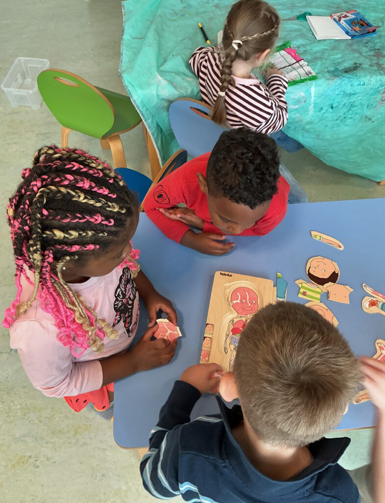 Kinder sitzen an Tischen und puzzeln