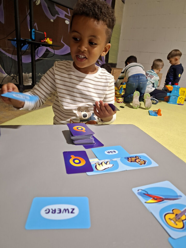 Kinder sitzen am Tisch oder hocken auf dem Fussboden und spielen