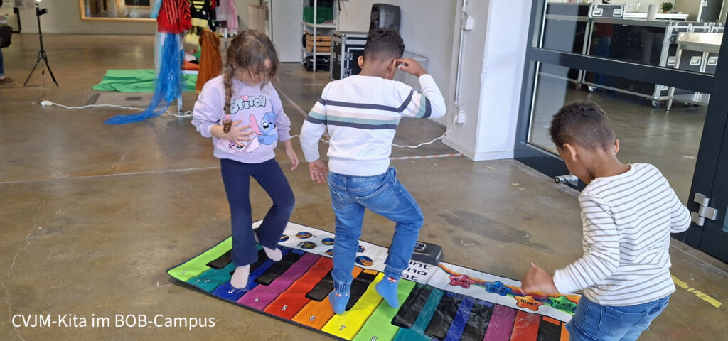 Kinder bewegen sich auf einer bunten Klaviertanzmatte in der Stadtteilbibliothek