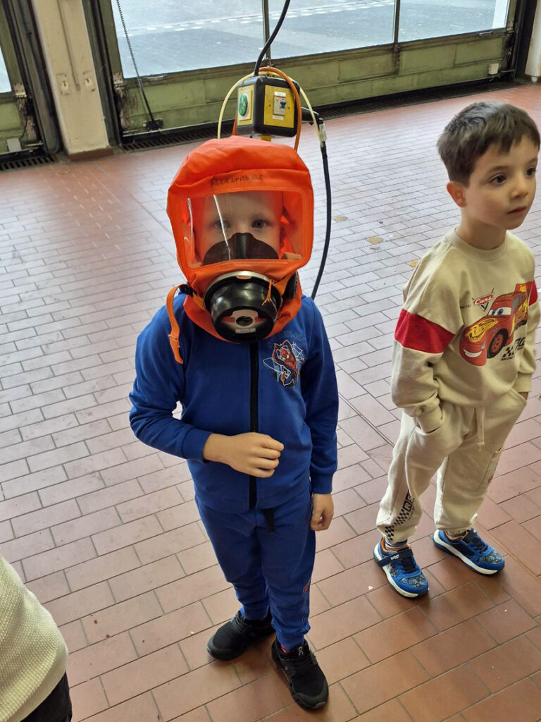 Ein Kind traegt eine Atemschutzmaske im Geraetehaus der Feuerwehr