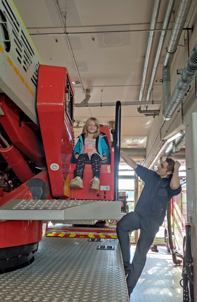 Ein Kind sitzt probeweise im Steuersitz eines grossen Leiterfahrzeugs der Feuerwehr Wuppertal