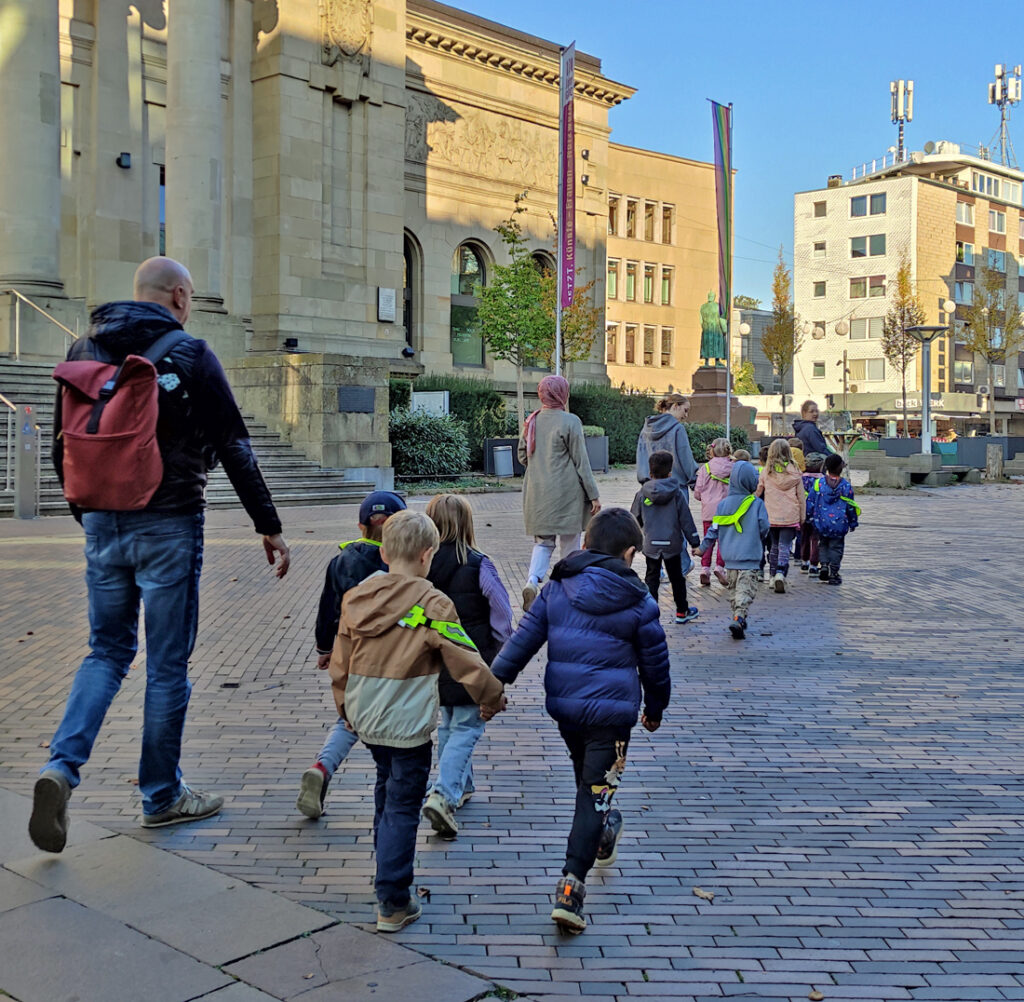 Kinder und Erwachsene gehen über einen gepflasterten Platz in Wuppertal