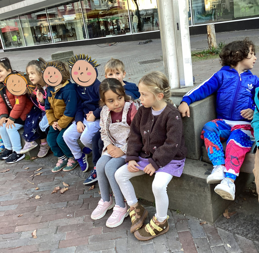 Kinder sitzen auf einer Bank in einer Wuppertaler Fussgaengerzone
