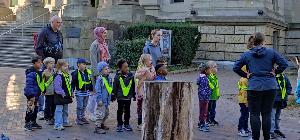 Kinder und Erwachsene stehen in einer Schlange vor einem Gebaeude